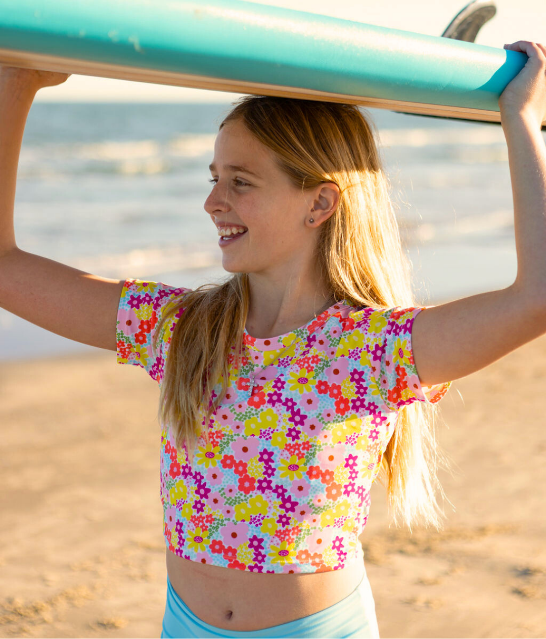 Young girl holding a surfboard on a beach